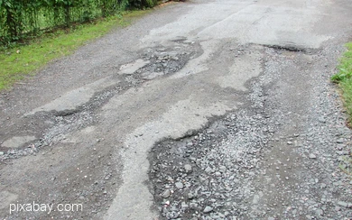 Straße mit großen Schlaglöchern und beschädigtem Asphalt