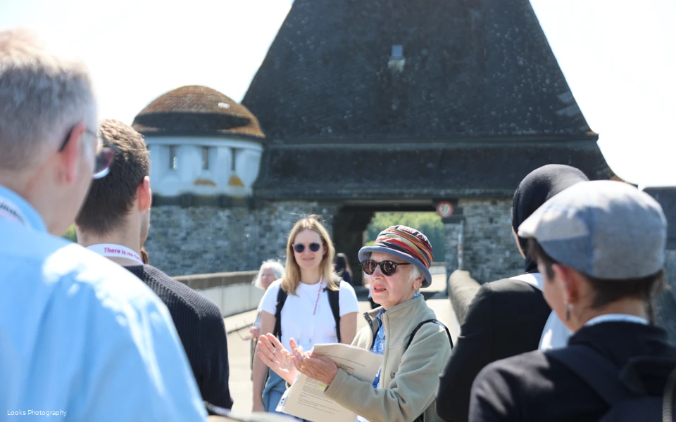 Gruppe im Rahmen einer Gästeführung auf der Staumauer mit Fokus auf die Gästeführerin
